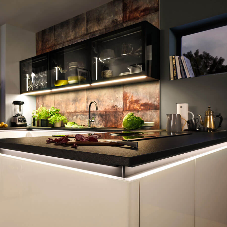 Kücheninsel mit beleuchteter Rückwand im Hintergrund